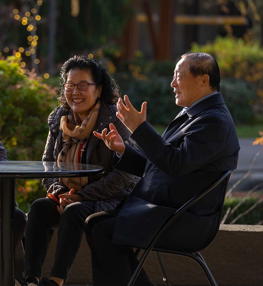 Asian American seniors sitting at an outdoor table laughing
