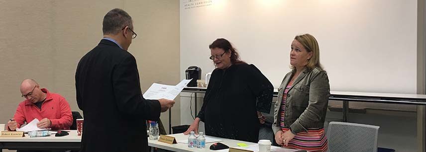 two Verdant board members behind table, welcoming man in dark black suit