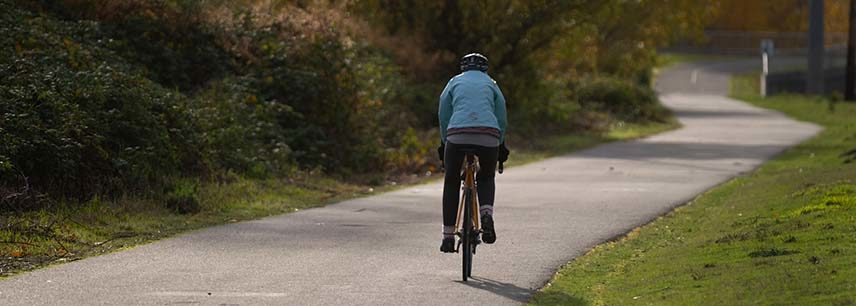person in blue winter coat riding bike on path through park